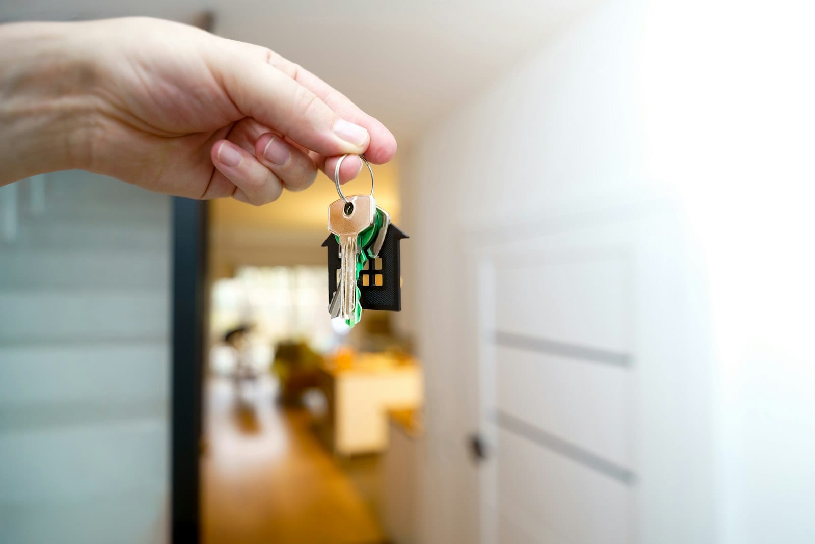 Hand holding house keys with a house-shaped keyring